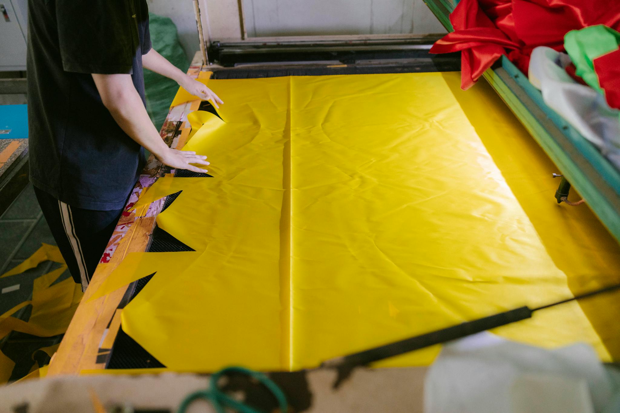 A person cutting yellow fabric for textile production in a workshop.