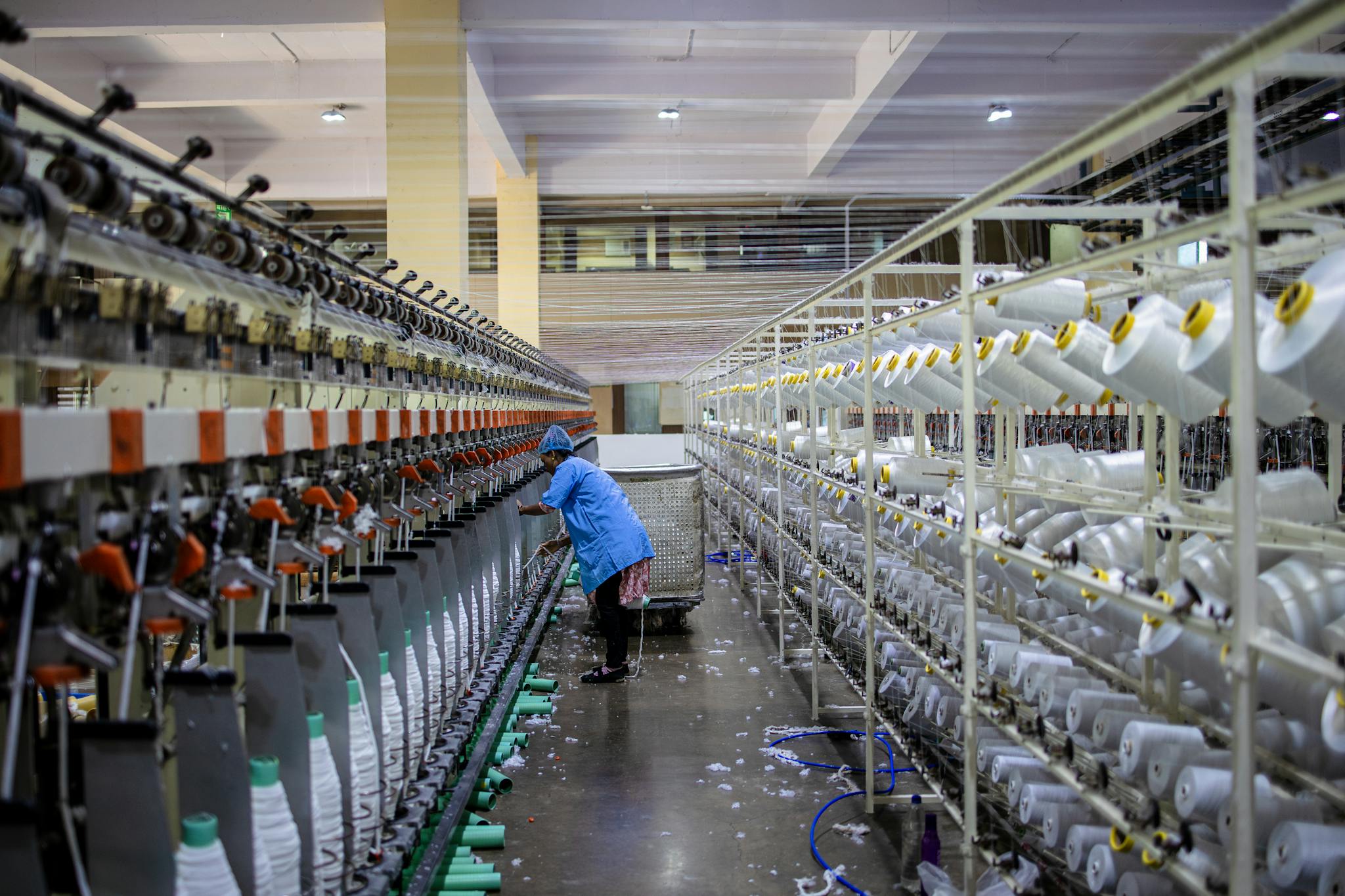 A textile worker handling machinery in a modern factory setting.