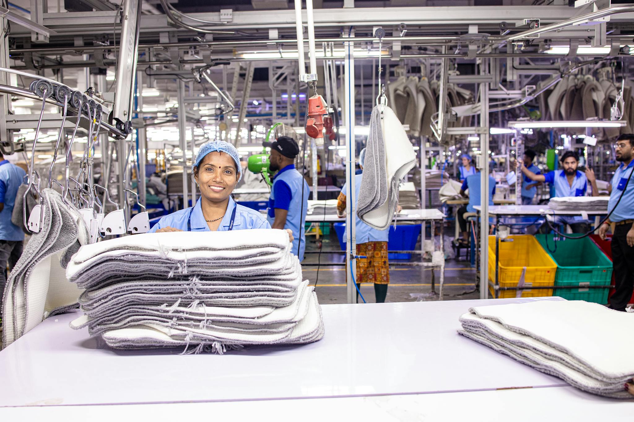 Female factory worker in a bustling textile manufacturing environment.
