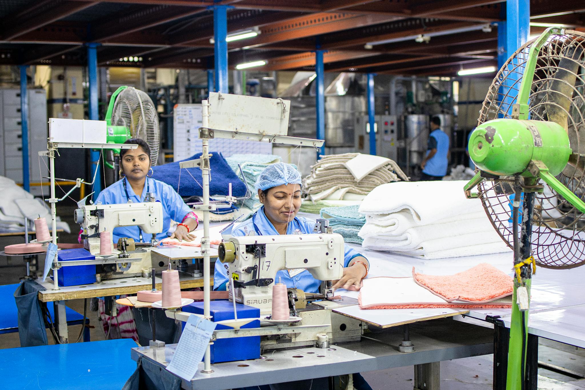 Female workers sew textiles in an Indian factory, showcasing industrial textile production.